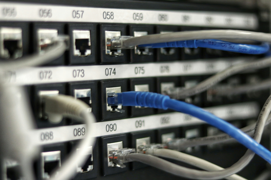 Photo of a server rack as seen from the back, with ethernet cables coming out
